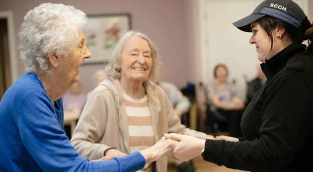 elderly woman dancing with a caregiver in a senior living community.