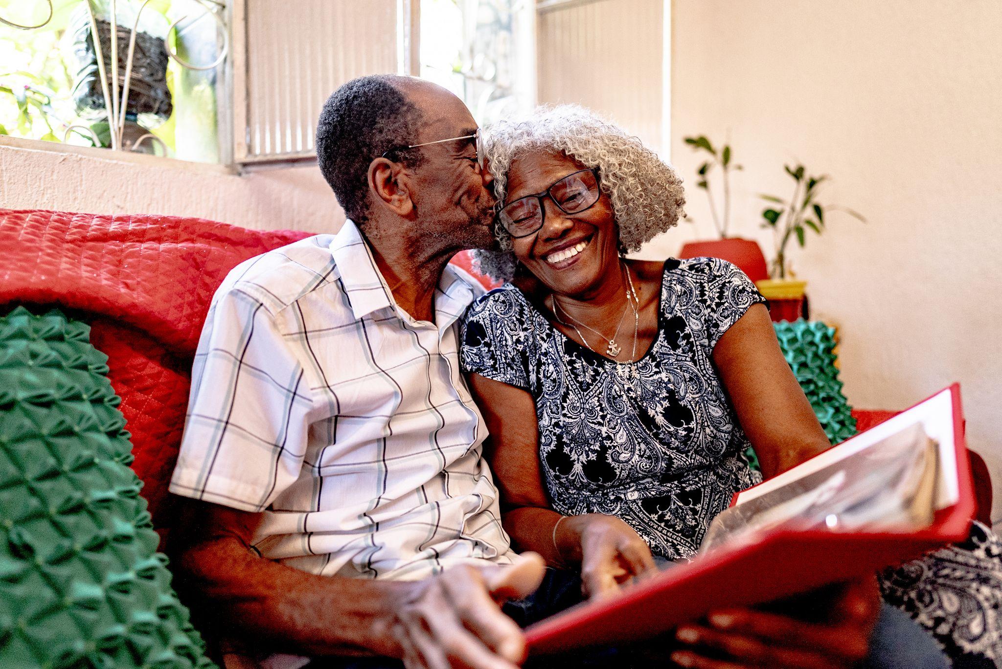 Senior man kissing significant other on head while looking at photo album