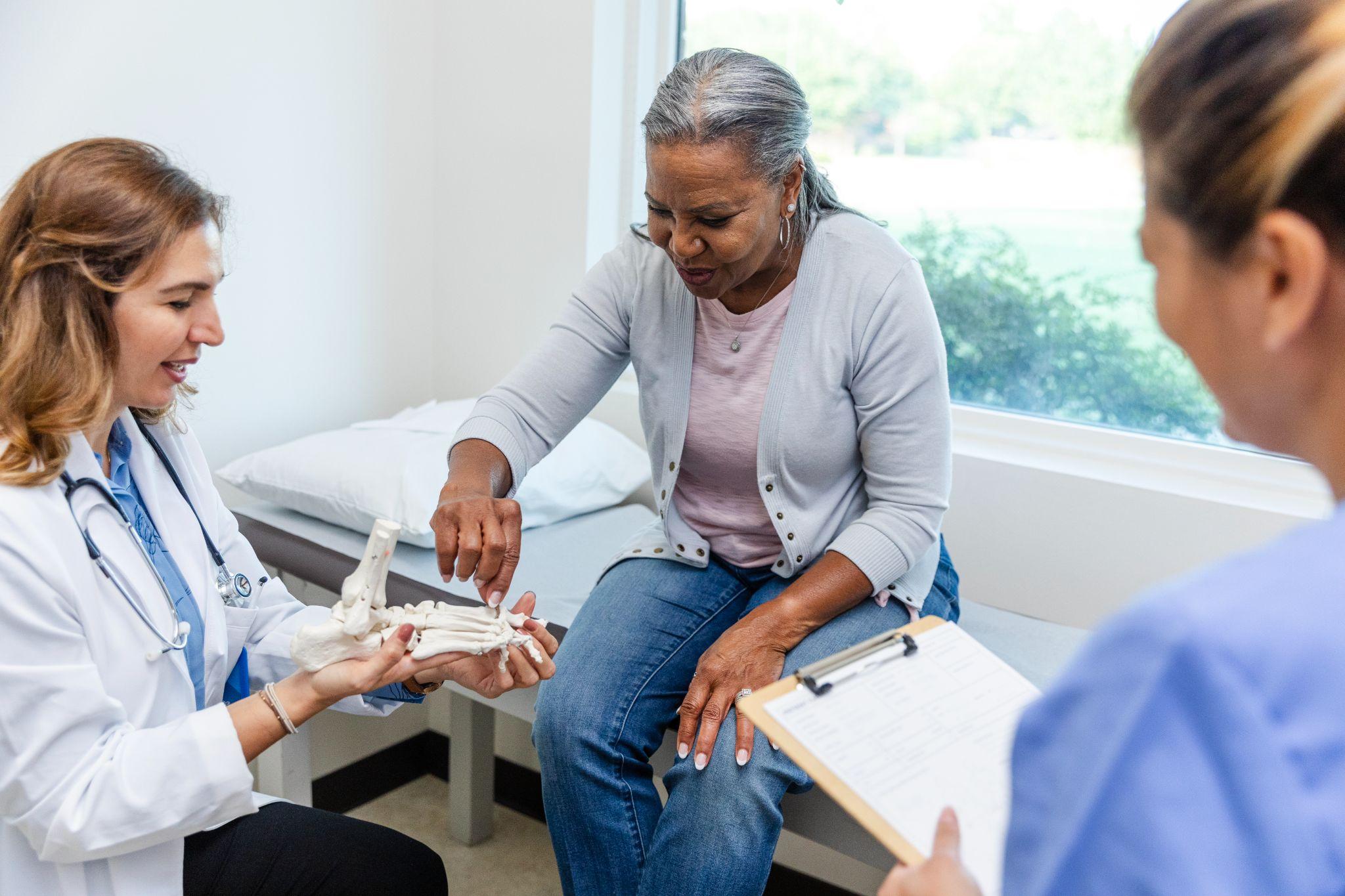 An older woman goes to the doctor and speaks to them regarding bone health.
